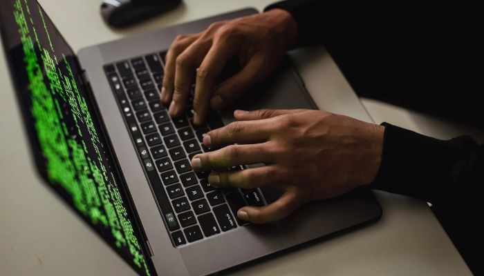 Crop cyber spy hacking system while typing on a laptop. — Pexels
