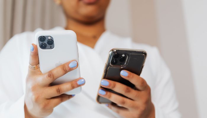 A person holding two iPhones.— Pexels