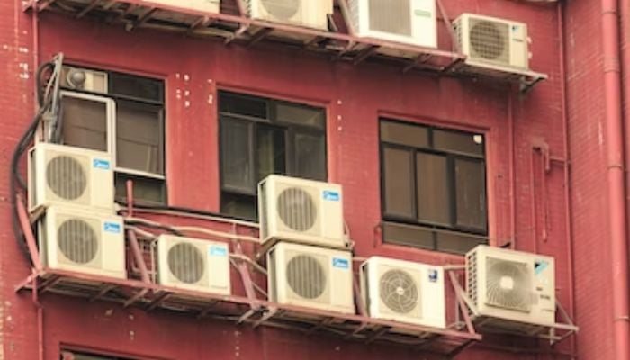 The image shows several air conditioner outers in a building. — Unsplash