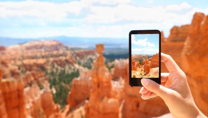An undated image illustrating a person taking a picture with a phone camera. — Canva
