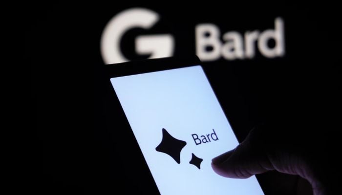 The image shows a person using Bard on their phone.— Unsplash