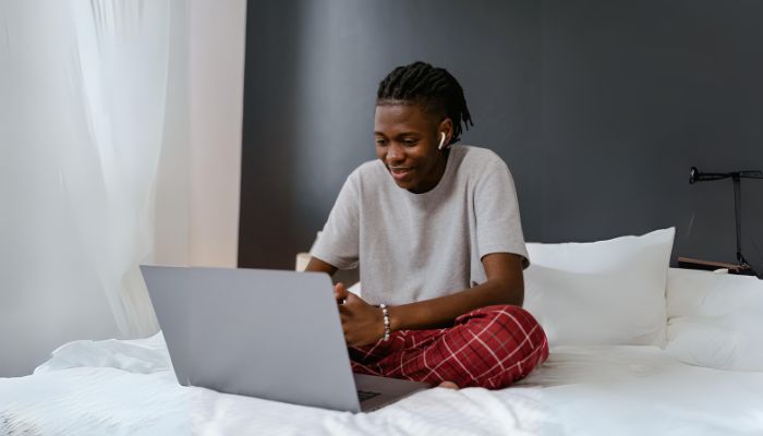 An undated image illustrating a person wearing AirPods while using a laptop. — Canva