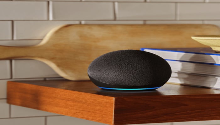 The image displays an Amazon Echo dot placed on wooden table. — Amazon