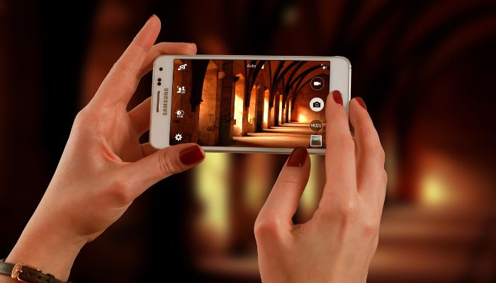 An undated image illustrating a person holding a Samsung mobile. — Canva