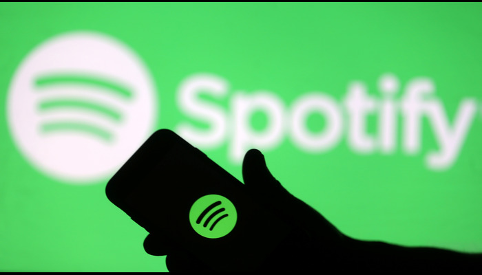 A smartphone is seen in front of a screen projection of Spotify logo, in this picture illustration taken April 1, 2018. — Reuters