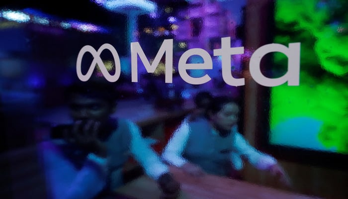 People are seen behind a logo of Meta Platforms, during a conference in Mumbai, India, September 20, 2023. — Reuters