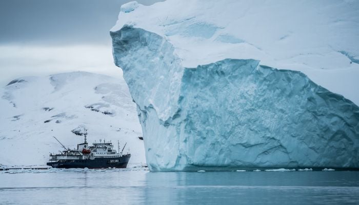 The image shows a ship with an iceberg. — Unsplash