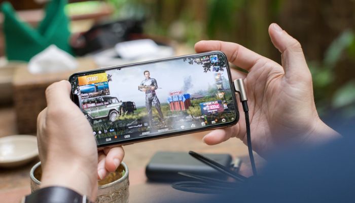 The image shows a person playing a game on their smartphone. — Unsplash