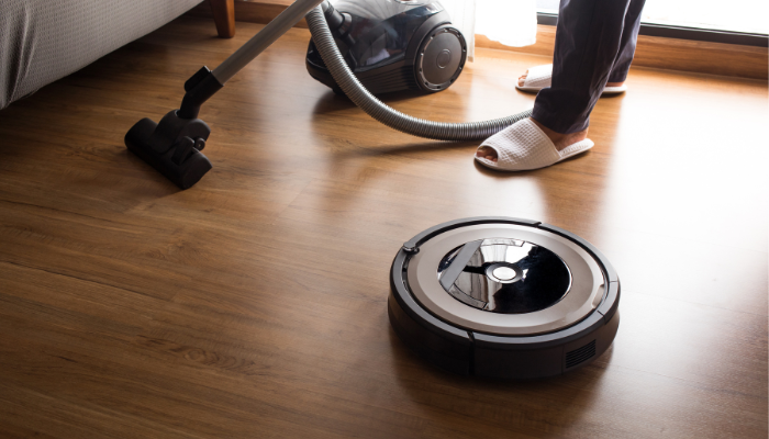 An undated image illustrating a robot vacuum cleaner and a handheld vacuum cleaner. — Canva