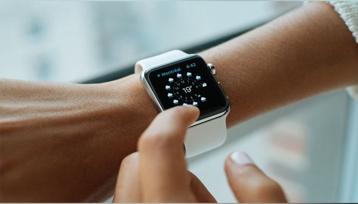 An illustration of a smartwatch, strapped to a persons wrist, displaying weather — Unsplash