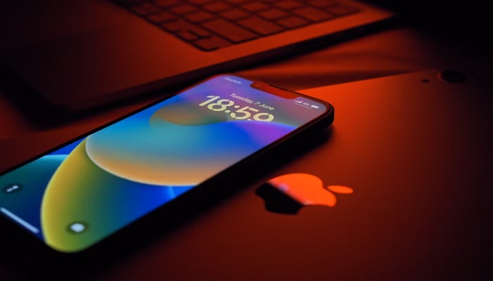 The image displays an iPhone placed besides a laptop. — Unsplash