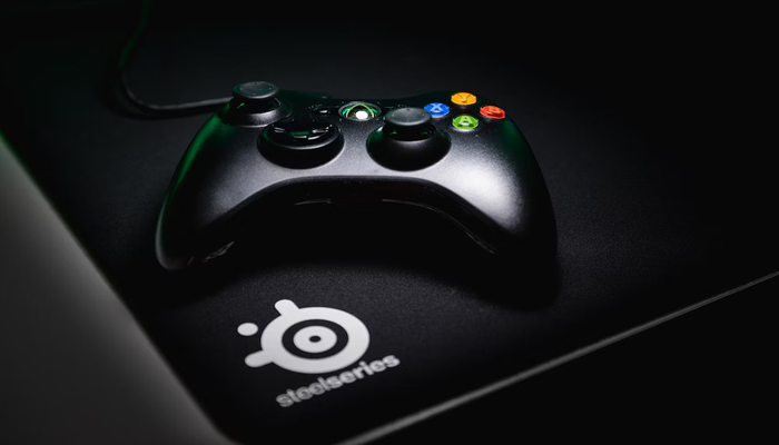 The image displays an Xbox console controller placed on a mouse pad. — Unsplash