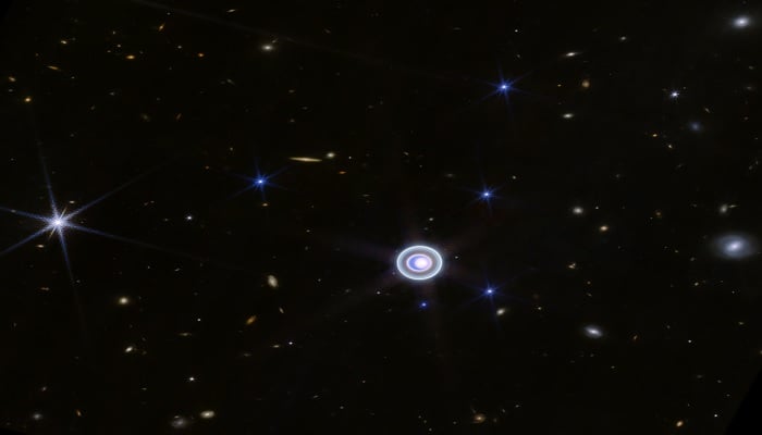 This wide-field image of Uranus from NIRCam (Near-Infrared Camera) on NASA’s James Webb Space Telescope shows the planet amid a smattering of distant background galaxies. This image also includes 14 of the planet’s 27 moons: Oberon, Titania, Umbriel, Juliet, Perdita, Rosalind, Puck, Belinda, Desdemona, Cressida, Ariel, Miranda, Bianca, and Portia. — NASA, ESA