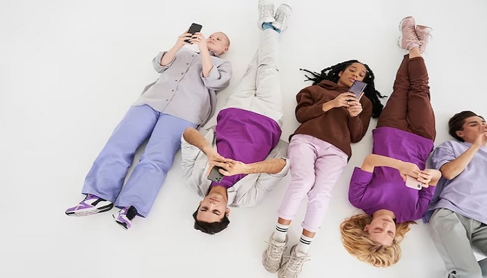 The image shows youngsters using their phones while lying on the floor. — Freepik