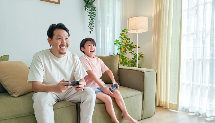 The image shows a person and a child playing a video game. — Unsplash