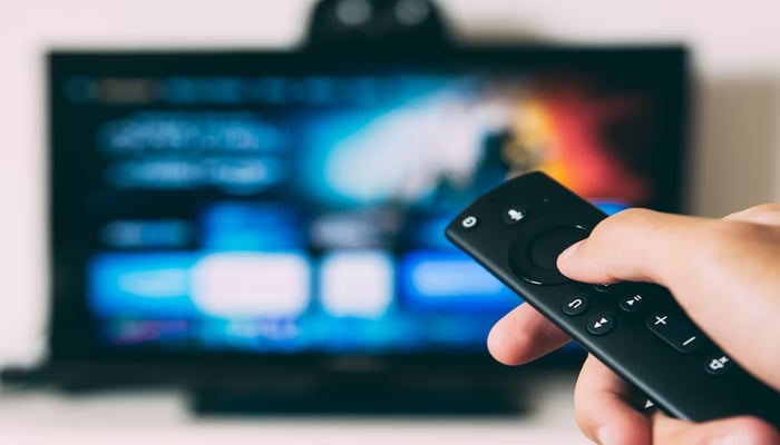 An undated image shows a person using a TV remote. — Unsplash