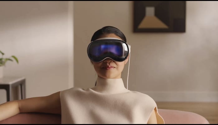 The image shows a girl wearing a Vision Pro headset. — Apple
