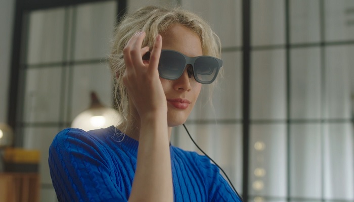 The image shows a woman wearing XREAL Air 2. — XREAL