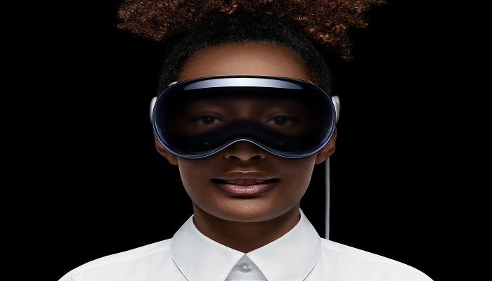 The image shows a woman wearing an Apple Vision Pro. — Apple