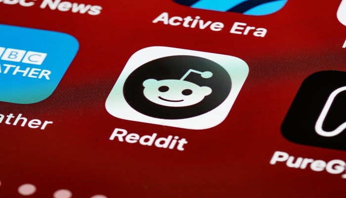 The image shows Reddit logo on phone scren. — Pexels