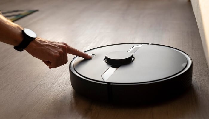 The image shows a robot vacuum in living room. — Freepik