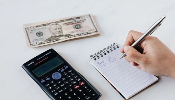 The image shows a person writing in a notebook. — Pexels