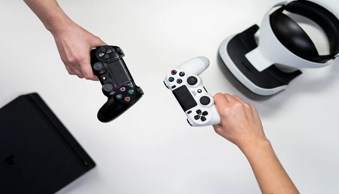 The image shows a person holding white and black Xbox One controller. — Pexels