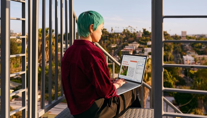 The image shows a person using a Surface laptop. — Microsoft