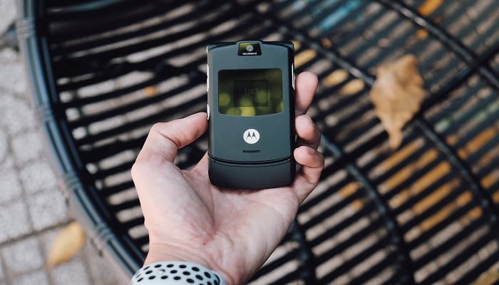 The image shows a Motorola phone in a persons hand. — Unsplash