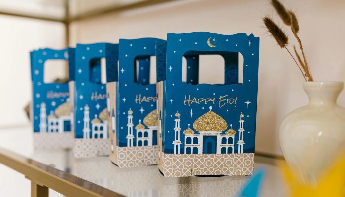 The image shows white and blue gift boxes that read Happy Eid. — Pexels