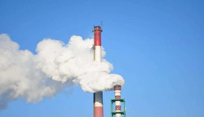 The image shows smoke coming out of a factory. — Pexels
