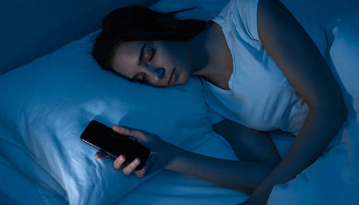 An undated image of a girl sleeping with her iPhone in her hands. — Pixabay
