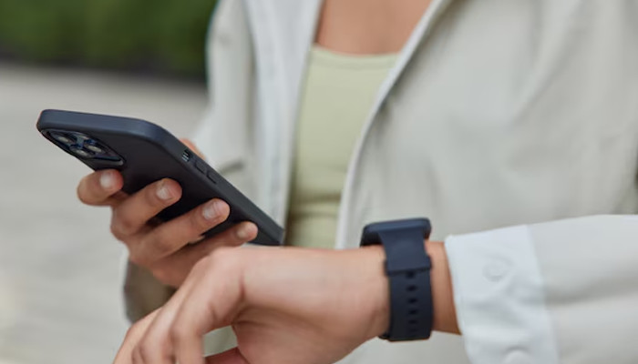 An undated image showing a girl trying to connect her smartwatch with her mobile device. — Freepik