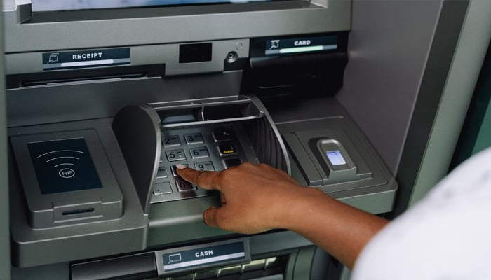 An undated image of a person using an ATM. — Unsplash