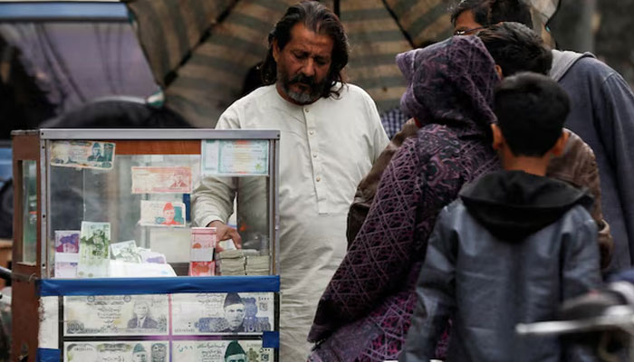 A currency broker stands near his booth, which is decorated with pictures of currency notes, while dealing with customers, along a road in Karachi, Pakistan January 27, 2023. — Reuters
