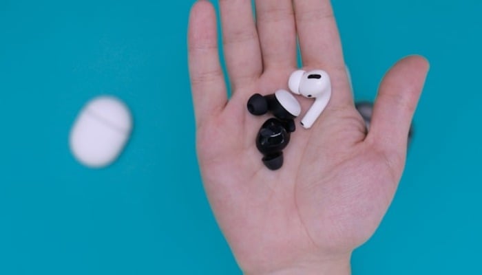 An undated image of a person holding AirPods. — Unsplash