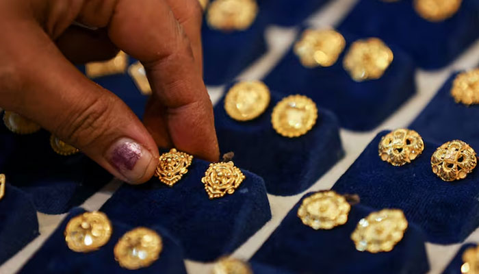 A woman picks a gold earring at a jewellery shop in the old quarters of Delhi, India, May 24, 2023. — Reuters