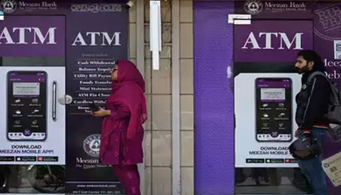 An undated image of people waiting in que outside an ATM. — AFP