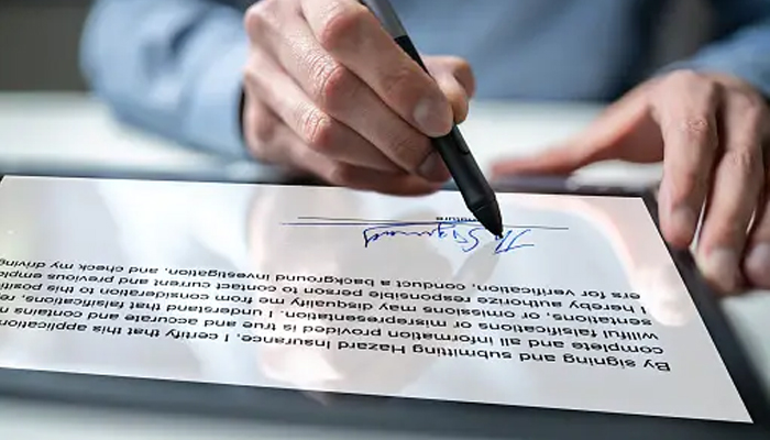 An undated image showing a person e-signing on a document. — Unsplash