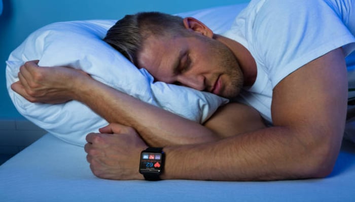 An undated image of a person sleeping with a smartwatch on the writs. — Unsplash