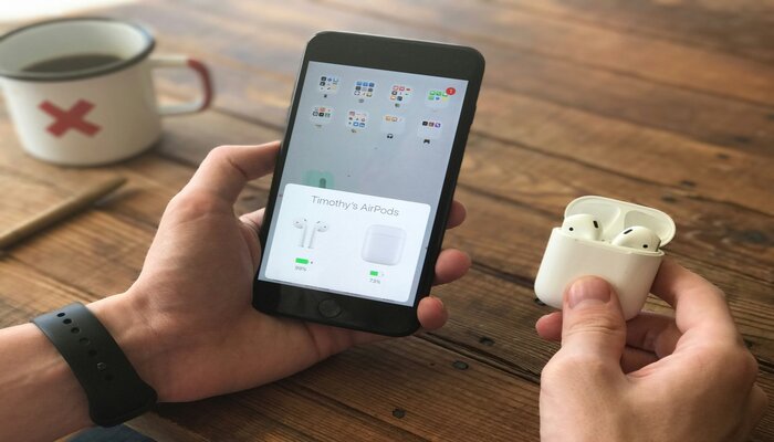 An undated image of a person holding Airpods and a smartphone. — Unsplash