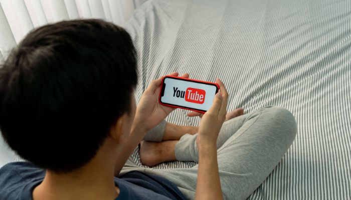 An undated image of a person using YouTube on the mobile phone. — Canva