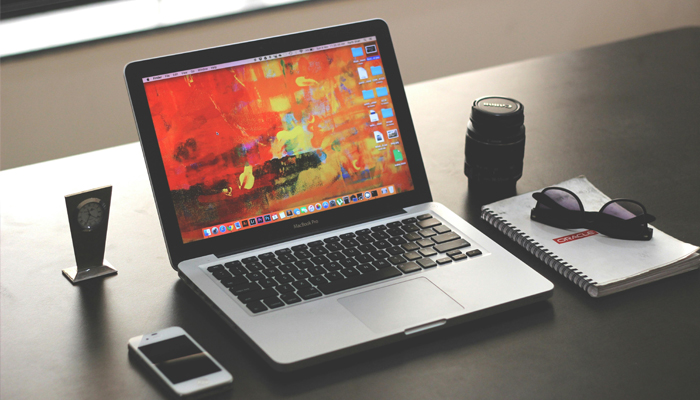 An undated image showing Apple MacBook placed on table along with other essentials. — Pexels