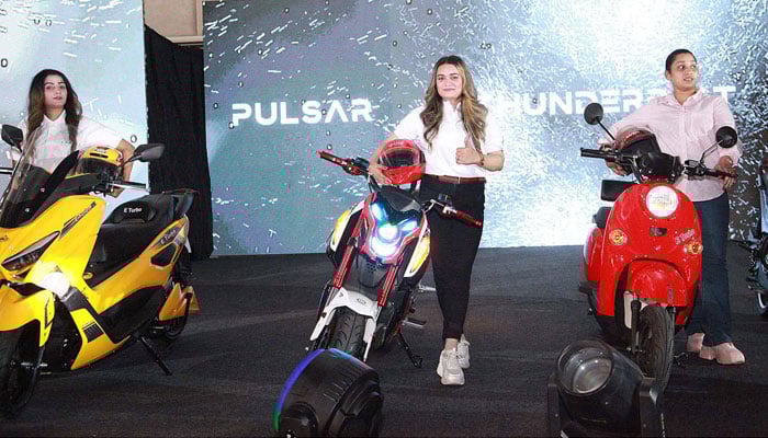 Girls posing with the newly launhed electric motorcycles by eTurbo Motors on October 16, 2024 at a Pearl Continental Hotel in Karachi. — APP