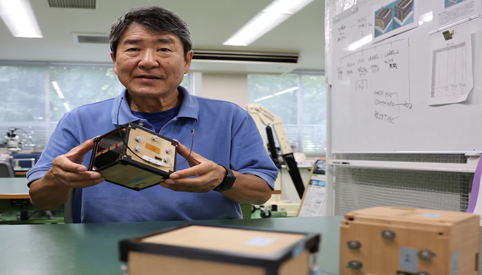 The image shows a former Japanese astronaut and professor at Kyoto University holding in hands an engineering model of LignoSat at Kyoto University in Kyoto, Japan, October 25, 2024. — Reuters