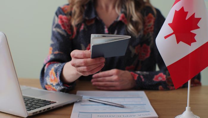 An undated image of a person holding a Canadian visa. — Canva