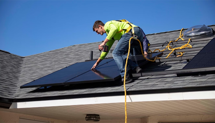 An undated image of a person installing solar panel on a rooftop. — Unsplash