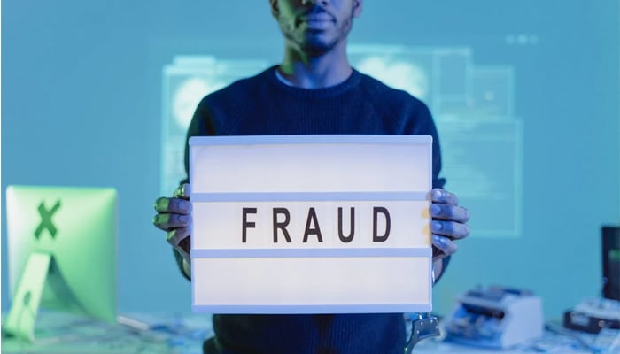 An undated image of a person holding a fraud sign. — Pexels