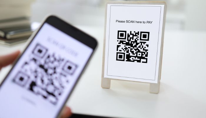 An undated image of a person scanning a QR code from their phone. — Canva