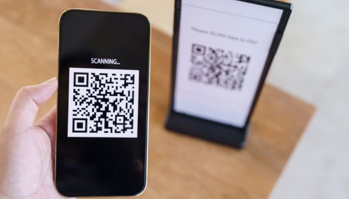 An undated image of a person scanning a QR code. — Canva